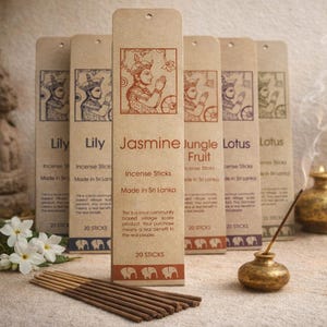 Puede incluir: Palitos de incienso con varios aromas, incluyendo Lirio, Jazmín y Loto, se muestran en la imagen. El embalaje es de color marrón claro con ilustraciones y texto. Los palitos están hechos en Sri Lanka y vienen en paquetes de 20.