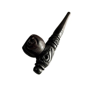 Puede incluir: Una pipa de madera marrón oscuro con tallas intrincadas. La cazoleta de la pipa es redonda y tiene un diseño tallado. La boquilla de la pipa es larga y delgada.