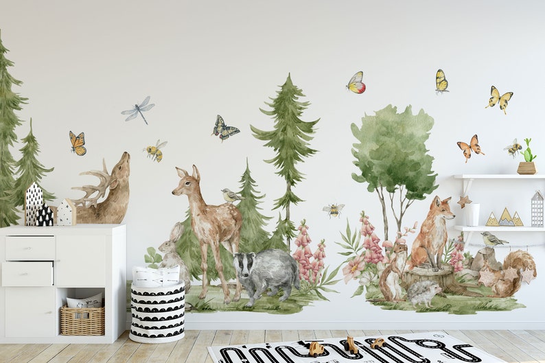May include: A watercolor-style wall decal set featuring woodland animals, including a deer, fox, badger, and squirrel. The decals are surrounded by trees, flowers, butterflies, and bees, creating a whimsical forest scene.