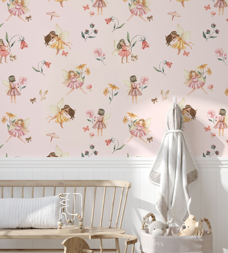 May include: Pink wallpaper with a repeating pattern of fairies, flowers, and butterflies. The wallpaper is shown in a room with a white wainscoting, a wooden bench, and a basket of toys.