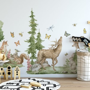 May include: A watercolor-style wall decal featuring a forest scene with a deer, fox, squirrel, and butterflies. The decal is applied to a white wall in a child's room with a wooden shelf, toys, and a black and white rug.