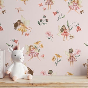 May include: Pink wallpaper with a repeating pattern of fairies, flowers, and mushrooms. The fairies are wearing yellow, pink, and red dresses with wings. The flowers are in shades of pink, yellow, and red. The mushrooms are brown. A white stuffed unicorn is sitting in front of the wallpaper.