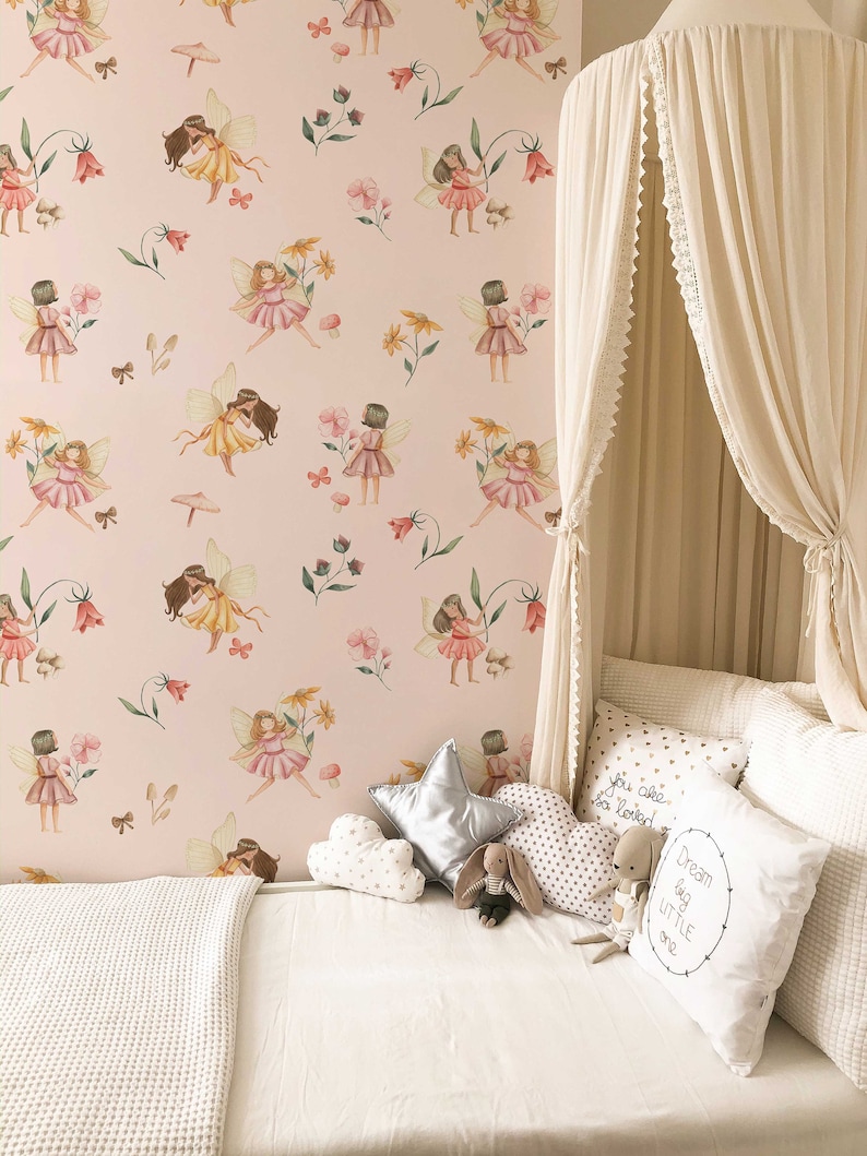 May include: A white canopy bed with a pink and green fairy wallpaper. The bed is decorated with white and gold pillows, a silver star pillow, and a stuffed bunny. The pillows have text that reads "You are so loved" and "Dream big little one".