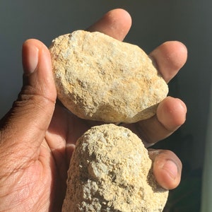 Peut inclure: Deux pierres rondes, naturelles, de couleur beige et à la texture rugueuse. Les pierres sont de taille et de forme similaires.