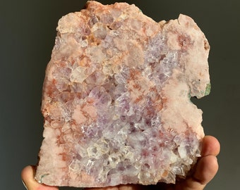 Op de afbeelding: Een grote amethistgeode met een roze en paarse kristallisatie. De geode heeft een ruwe, natuurlijke textuur en is een prachtig voorbeeld van een natuurlijk kristal.