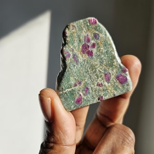 May include: A green and red ruby in matrix crystal. The crystal has a rough, natural shape and is speckled with red ruby inclusions.