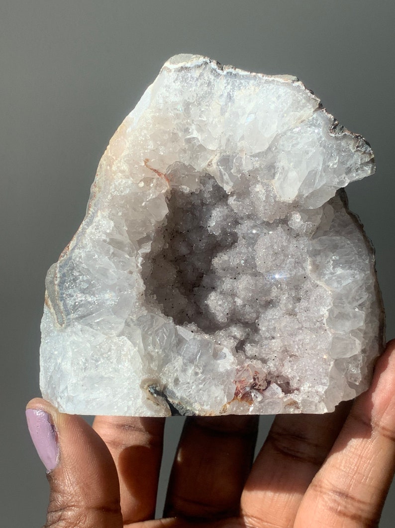 K&ouml;nnte beinhalten: Ein wei&szlig;er Kristallgeode mit einer gro&szlig;en, offenen H&ouml;hle. Das Innere des Geoden ist mit kleinen, wei&szlig;en Kristallen ausgekleidet. Der Geode hat ein raues, nat&uuml;rliches &Auml;u&szlig;eres.