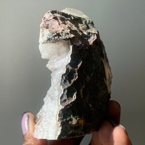K&ouml;nnte beinhalten: Eine gro&szlig;e, wei&szlig;e Kristallgeode mit einer rauen, braunen und grauen Au&szlig;enseite. Die Geode ist teilweise ge&ouml;ffnet und zeigt die wei&szlig;en Kristalle im Inneren.