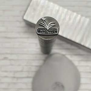 May include: A silver metal stamp with the text "Green Desert Creations" and a stylized image of a plant with a flower.