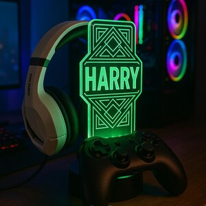 May include: A personalized green LED gaming lamp with the name "HARRY" displayed. The lamp is next to a black game controller and white headphones. The words "DESIGN 3" are at the bottom.
