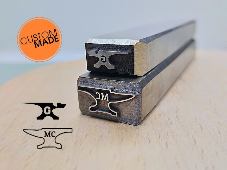 Pu&ograve; includere: Due timbri metallici con un design a forma di incudine. Il timbro superiore ha la lettera "G" sull'incudine. Il timbro inferiore ha le lettere "CM" sull'incudine. I timbri sono su una superficie di legno. Il testo "CUSTOM MADE" &egrave; in un cerchio sul lato sinistro dell'immagine.