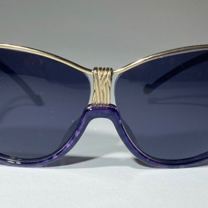 May include: Purple cat-eye sunglasses with a gold metal frame.