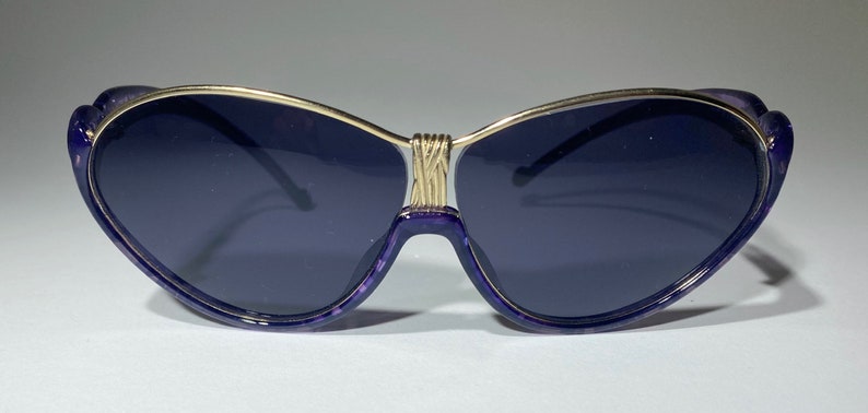 May include: Purple cat-eye sunglasses with a gold metal frame.
