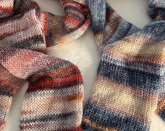 May include: Two hand-knitted scarves. One scarf features a color palette of red, orange, pink, and cream stripes. The other scarf has blue, cream, and orange stripes. Both scarves are made of a soft, textured yarn.