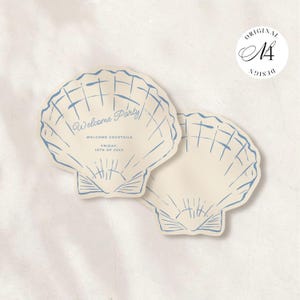 May include: Two die-cut scallop shell-shaped cards in cream with blue line art illustrations. The top card features the text Welcome Party, WELCOME COCKTAILS, FRIDAY, 16TH OF JULY in blue ink. A circular logo in the top right corner reads ORIGINAL DESIGN.
