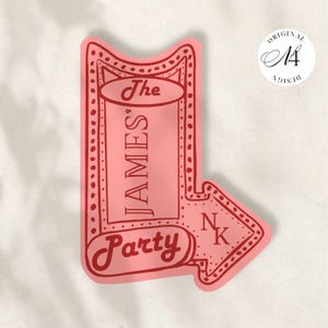 Può includere: Un adesivo rosa e rosso a forma di freccia direzionale. Il testo recita The James' Party con le lettere NK posizionate nella punta della freccia. Il design presenta un bordo punteggiato e uno stile a tendone vintage con un centro rosa chiaro.