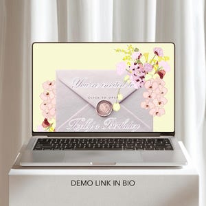 May include: A laptop displays a digital invitation with the text "You're invited to Kelly's Birthday." The invitation is designed as a light gray envelope with a wax seal and floral accents. The laptop sits on a white surface.