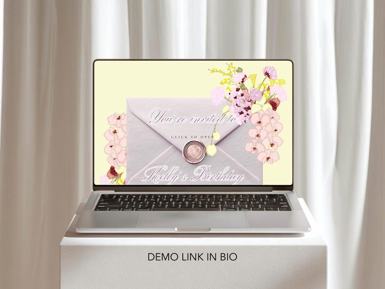 May include: A laptop displays a digital invitation with the text "You're invited to Kelly's Birthday." The invitation is designed as a light gray envelope with a wax seal and floral accents. The laptop sits on a white surface.