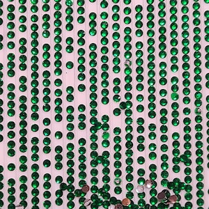 May include: A sheet of green rhinestones arranged in rows on a white background. The rhinestones are small and round, and they are arranged in a regular pattern.