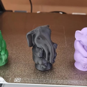 Peut inclure: Trois figurines imprimées en 3D : une créature verte au long museau, une créature noire à tête d’éléphant et tentacules, et une créature violette ressemblant à une gargouille.