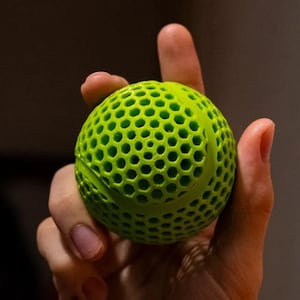 May include: A bright green ball with a honeycomb pattern. The ball is made of a soft, flexible material.