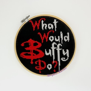 May include: A black and white cross-stitch embroidery hoop with the text "What Would Buffy Do?" and the "Buffy the Vampire Slayer" logo in red.