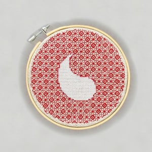 May include: A red and white embroidery hoop with a white outline of a crescent moon shape on a red background. The background is filled with a repeating pattern of small red flowers.