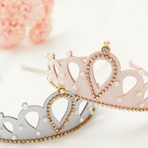 May include: Two princess crowns, one pink and one silver, with pearl and rhinestone accents. The crowns are made of felt and have a headband.