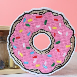 May include: Pink embroidered donut patch with colorful sprinkles.