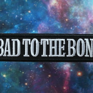 Peut inclure: Écusson brodé noir avec du texte blanc qui dit "Bad to the Bone".