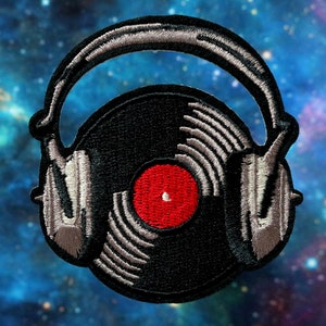 Puede incluir: Un parche bordado en negro y plata de un disco de vinilo con auriculares en la parte superior. El disco tiene una etiqueta central roja.