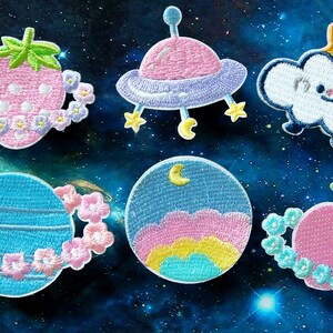 May include: Six embroidered iron-on patches with a space theme. The patches feature a pink strawberry with a ring of flowers, a pink and purple spaceship, a white cloud with a yellow star, a blue planet with a ring of flowers, a blue and pink planet with a crescent moon, and a pink peach with a ring of flowers.