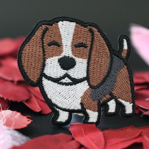 Könnte beinhalten: Gestickter Aufnäher eines braunen und weißen Beagles mit schwarzer Nase und einem schwarzen und grauen Halsband. Der Beagle lächelt und hat die Zunge herausgestreckt.