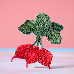 Puede incluir: Un rábano rojo bordado con hojas verdes. El rábano es una verdura popular y se usa a menudo en ensaladas y otros platos.