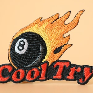 May include: Embroidered patch with a black 8-ball on fire and the text "Cool Try" in red.