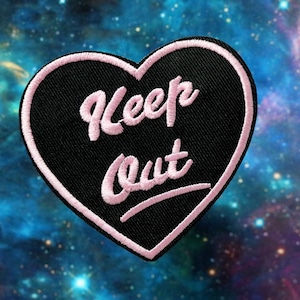 May include: Black heart-shaped patch with pink embroidered text that reads "Keep Out".