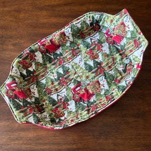 Könnte beinhalten: Roter und grüner Stoff-Brotkorb mit einem Weihnachtsbaum- und rotem LKW-Muster. Der Korb ist aus gestepptem Stoff und hat einen roten Rand.