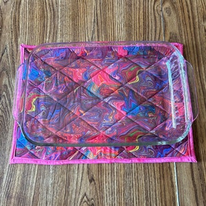 May include: A pink quilted hot pad with a glass baking dish on top. The hot pad has a colorful swirl pattern in shades of pink, blue, purple, and red.