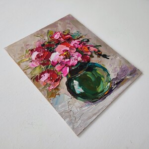 Puede incluir: Pintura al &oacute;leo original de un bodeg&oacute;n floral. La obra presenta un ramo de flores rosas y rojas en un jarr&oacute;n verde. El fondo es de color beige neutro con pinceladas visibles, creando un efecto texturizado.