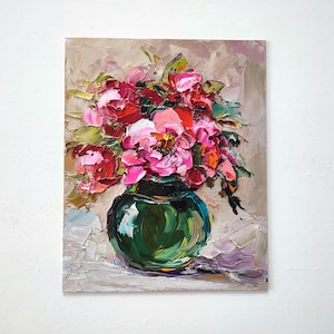 Puede incluir: Pintura al &oacute;leo de un ramo de peon&iacute;as rosas y rojas en un jarr&oacute;n de cristal verde. Las flores est&aacute;n pintadas con pinceladas gruesas, creando un efecto texturizado. El fondo es de color beige neutro.