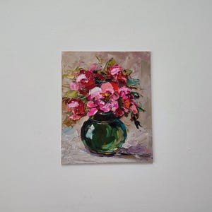Puede incluir: Pintura al &oacute;leo de un ramo de peon&iacute;as rosas y rojas en un jarr&oacute;n verde oscuro. Las flores est&aacute;n pintadas con pinceladas gruesas, creando un efecto texturizado. El fondo es de color beige neutro.