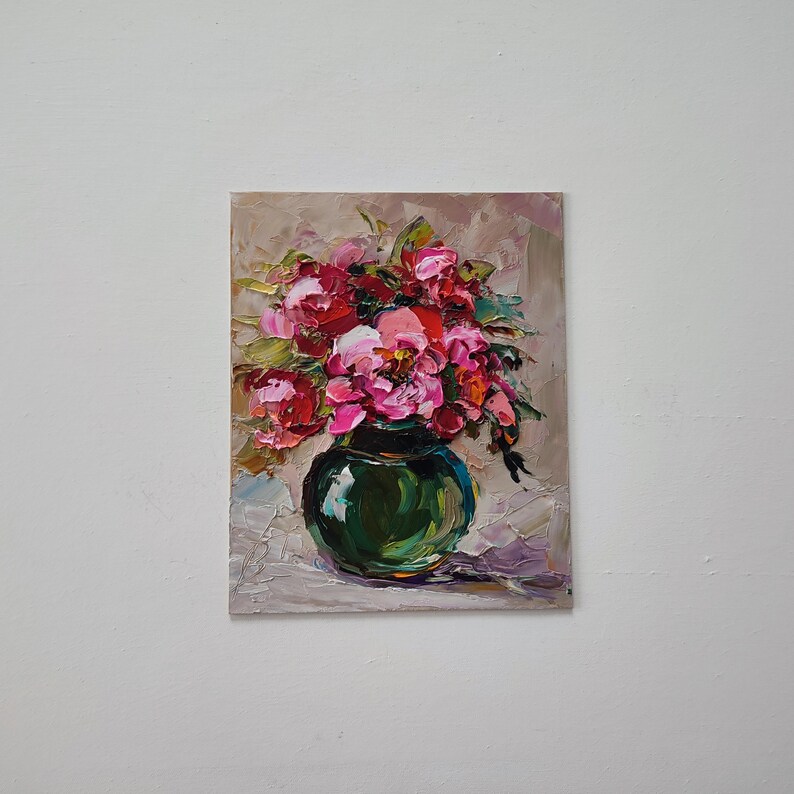 Puede incluir: Pintura al &oacute;leo de un ramo de peon&iacute;as rosas y rojas en un jarr&oacute;n verde oscuro. Las flores est&aacute;n pintadas con pinceladas gruesas, creando un efecto texturizado. El fondo es de color beige neutro.