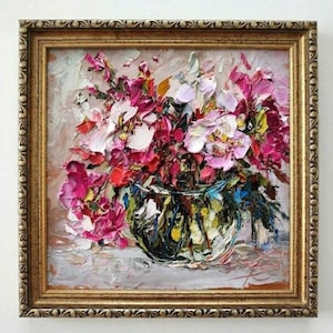 May include: An oil painting in a gold frame, depicting a vase of flowers. The flowers are predominantly pink, red, and white, with green and yellow details. The vase is a mix of green, blue, and yellow. The painting is created in a textured, impasto style.