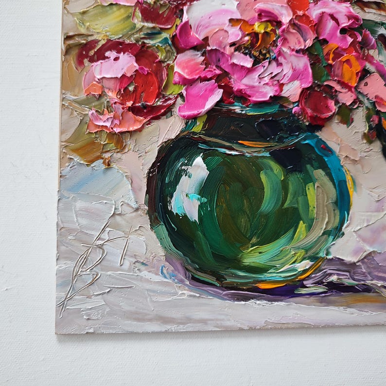 Puede incluir: Pintura al &oacute;leo de un ramo de flores rosas y rojas en un jarr&oacute;n verde oscuro. El jarr&oacute;n redondo descansa sobre una superficie blanca. La pintura utiliza una t&eacute;cnica de empaste, con pinceladas visibles.