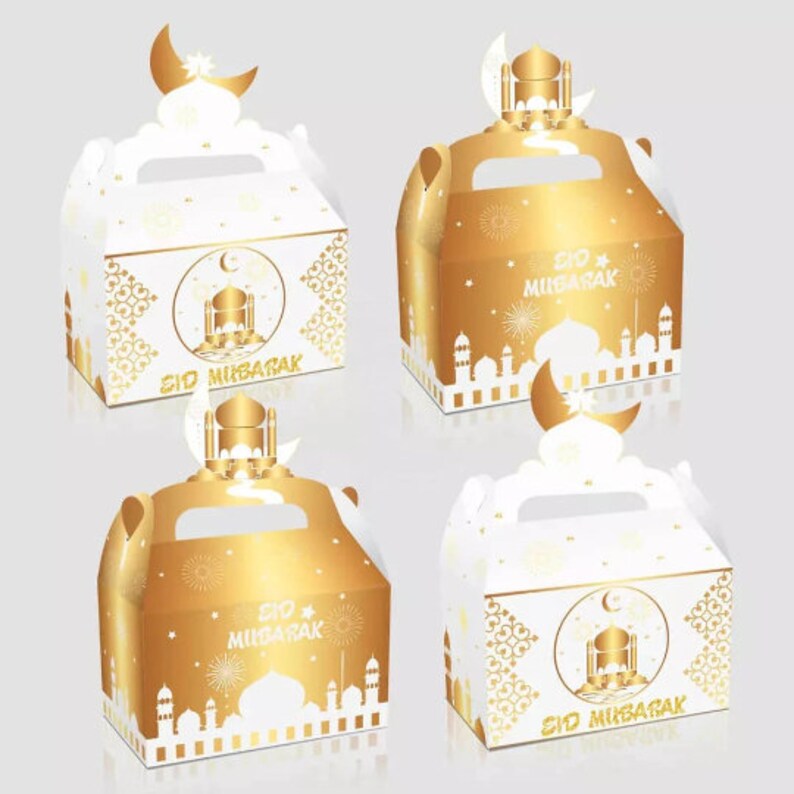 May include: Four gold and white favor boxes with a handle. The boxes have a mosque design and the text "Eid Mubarak" on them. The boxes are perfect for holding small gifts or treats.