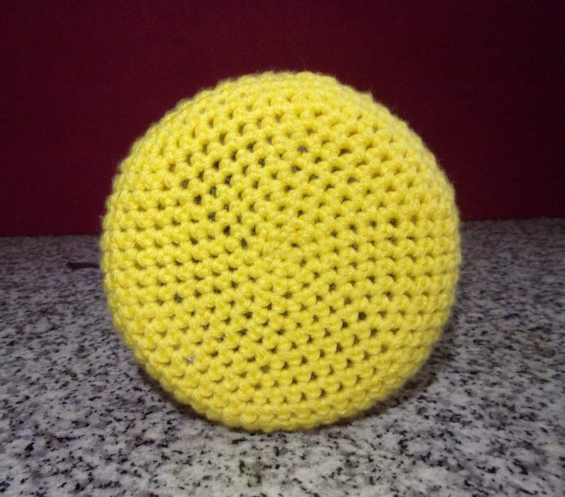 May include: A bright yellow crocheted round cushion or pouf. The cushion is made with a simple stitch pattern and has a smooth, even texture.