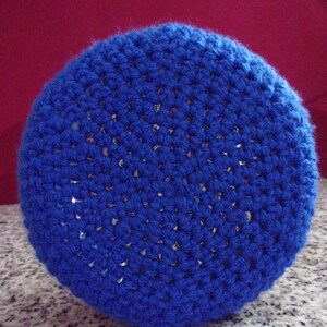 May include: A blue crocheted pot holder with a circular shape. The pot holder is made of a soft, textured yarn.