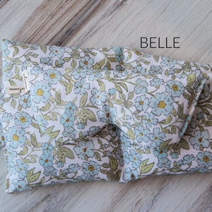 May include: A folded eye mask featuring a floral pattern with light blue and yellow flowers on a white background. The word "BELLE" is printed on the mask. The tag reads "FRANKIE JESS".