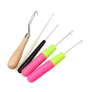 May include: A set of five latch hook tools with various handles. One features a light wood handle, one a thin cream handle, one a black handle, and two have bright pink handles with lime green accents. Each tool has a metal hook at the end.