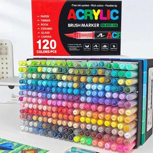 Puede incluir: Un juego de 120 rotuladores de pincel acrílico en una caja rectangular. El empaque muestra el texto ACRYLIC BRUSH MARKER y enumera superficies como papel, madera, piedra, cerámica, vidrio y lienzo. Los rotuladores están ordenados por color.